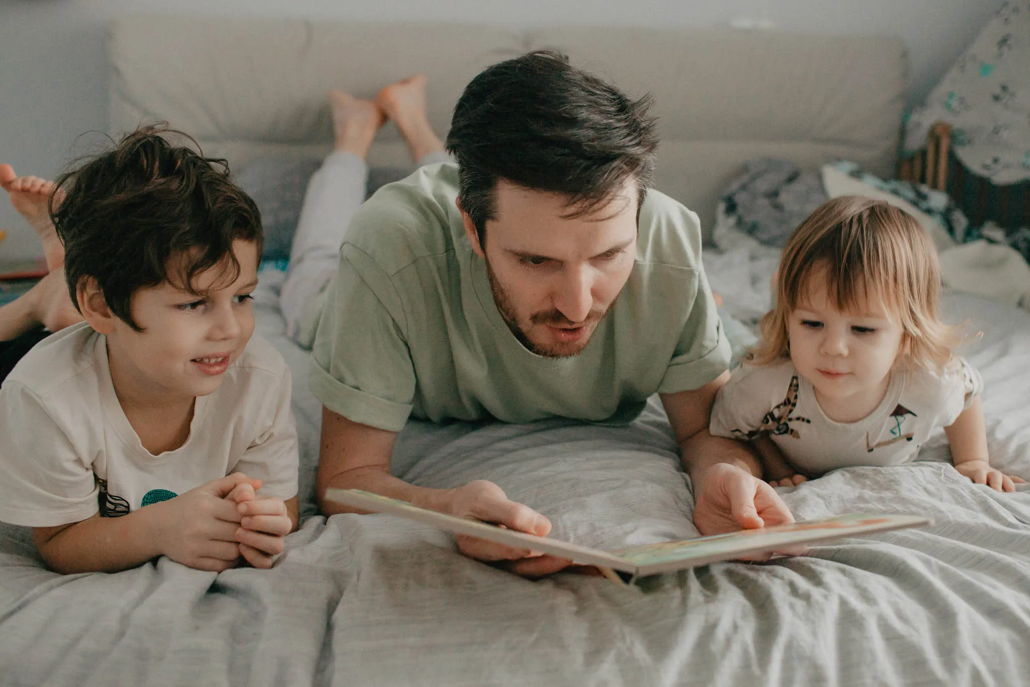 Padre lee con sus hijos en casa, mostrando el apoyo familiar en el desarrollo de la lectura.