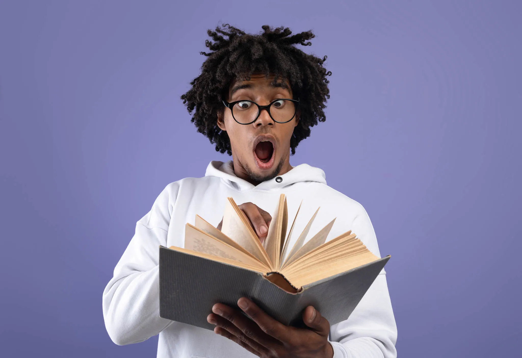 Joven sorprendido por una lectura que despierta curiosidad, imaginación y pensamiento crítico.