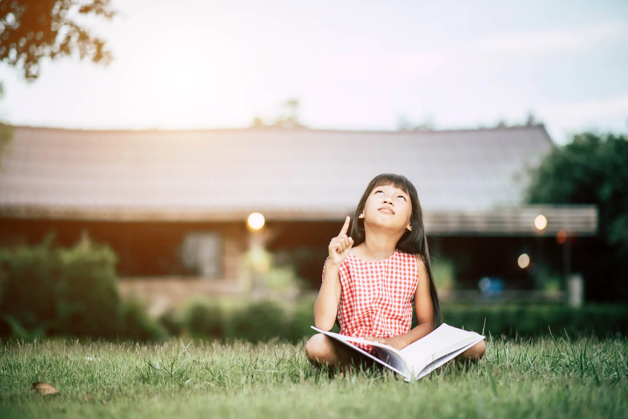 Niña leyendo al aire libre mientras reflexiona sobre una historia y desarrolla comprensión lectora.