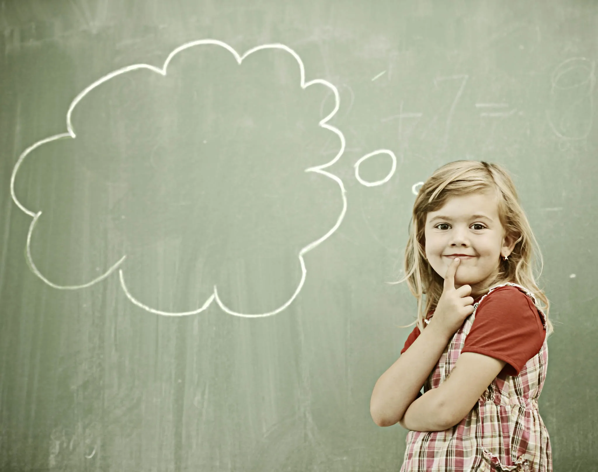 Niña frente a una pizarra con nube de pensamiento, asociada al pensamiento crítico en la educación.